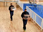 Dos trabajadores cargan con las urnas en la víspera de las elecciones catalanas