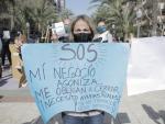 Una mujer perteneciente al sector hostelero de Alicante sostiene una pancarta en una manifestación