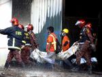 Los bomberos retiran a una víctima del incendio en una fábrica que ha dejado al menos 52 muertos.