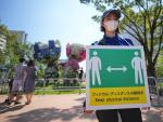 Una empleada con un cartel que pide mantener la distancia física para evitar el contagio de Covid en Tokio, Japón.
