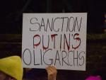 Un manifestante sostiene una pancarta "Sancionar a los oligarcas de Putin".