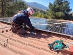 Un operario instala placas solares en una casa.