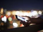 Una persona utilizando su teléfono móvil (smartphone) por la noche