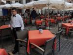 Un camarero anda entre mesas vacías en la Plaza Mayor de Madrid. Getty Images