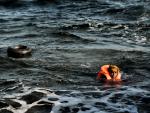 Un hombre nada en hacia la costa en frente de la isla de Lesbos/ AFP