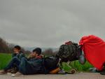 Un niño refugiado se cubre una manta roja mientras descansan cerca del campo de Idomeni, en la frontera de Grecia y Macedonia el 15 de marzo