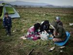 Refugee women prepare vegetables to cook, at the m