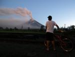 Un hombre observa el volcán Mayon mientras entra en erupción