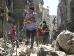 Dos hombres sirios mientras rescatan a dos bebés de una zona destruída tras un bombardeo en Alepo