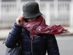 Una mujer sujeta su gorro en Pamplona para impedir que se lo lleve el viento. EFE/Jesús Diges