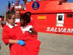 En Tarifa, una voluntaria de Cruz Roja traslada en sus brazos a una niña que viajaba en una de las pateras. EFE/A.Carrasco Ragel.