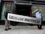 Dos empleados portan el logo Lehman Brothers para subastar sus obras de arte.