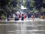 Numerosos filipinos atraviesan una calle inundada en Bulan