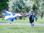 Una niña corre con una bandera escocesa mientras asisten a la marcha de All Under One Banner (AUOB) en Glasgow, Escocia. /EFE