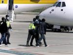 Agentes de la Policía Nacional trasladan hasta el avión a un grupo de inmigrantes desde Melilla a la península (imagen de archivo). /EFE
