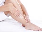 Una mujer se aplica crema hidratante en las piernas