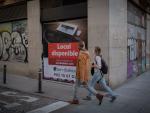 Dos personas caminan por una calle del Barrio Gótico ante un local cerrado en Barcelona
