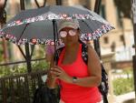 Una mujer se protege del sol con un paraguas durante un día de alerta roja por altas temperaturas en la ciudad de Murcia.