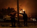 Bomberos voluntarios miran las llamas acercándose a una autopista en la zona de Afidnes, en Atenas (Grecia).