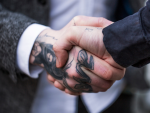 Hombre en traje con tatuaje en la mano.