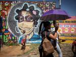 Los residentes de Soweto caminan frente a una obra de arte de graffiti en mitad del caos por la nueva cepa.