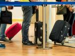Personas haciendo cola en el aeropuerto con sus maletas
