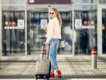 Una joven camina con su maleta dirección al aeropuerto