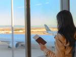 una chica en un aeropuerto mirando un avión antes de irse de viaje