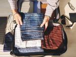 Un joven ordena prendas de ropa en la maleta para ir de viaje