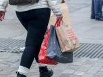 Una persona camina con varias bolsas de compras en la calle comercial de Preciados