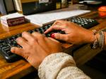 manos_mujer_escriben_teclado_ordenador_mesa_madera