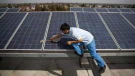 Un trabajador limpia una placa solar en la azotea de un edificio. EFE
