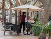 n camarero coloca una sombrilla en la terraza de un bar en la calle Betenchourt Alfonso de Santa Cruz de Tenerife.