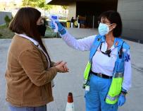 Una trabajadora toma la temperatura a una vecina antes de someterse a un test de antígenos en el Centro Cultural Lope de Vega, en Vallecas