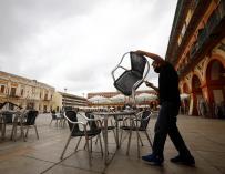 l trabajador de un bar prepara la terraza de un bar en Córdoba este domingo.
