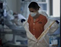 Una sanitaria se quita el traje de proteccion en la UCI del Hospital Universitario Ramón y Cajal