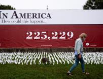 Un hombre camina frente a un cartel con la cifra de muertos por Covid-19 en EEUU, en Washington