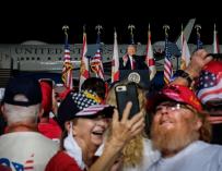 Dos asistentes se toman una fotografía durante el discurso del presidente estadounidense, Donald Trump (C), en un acto de campaña en Pensacola, Florida.