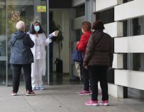 Una trabajadora sanitaria habla con varias pacientes que esperan en la puerta del Centro de Salud Doctor Tamames, en la zona básica de salud de Doctor Mamames, en Coslada, Madrid (España)