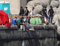 Varios inmigrantes magrebíes este jueves en el muelle de Arguineguín, en el que bajan las garrafas de agua hasta el mar con una cuerda para mantenerlas frescas.