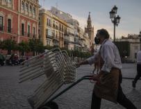 Un camarero recoge el mobiliario de la terraza de un bar de Sevilla, tras uno de los cierres de 2020.