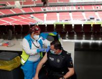 Un policía recibe la primera dosis durante el primer día de vacunación contra la covid-19 en el Wanda Metropolitano, el estadio del Atlético de Madrid.
