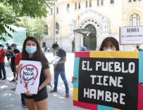 Una joven sostiene una pancarta donde se puede leer "El pueblo tiene hambre" durante una manifestación de las entidades ciudadanas.
