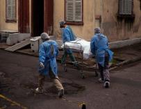 Enfermeros trasladan el cuerpo de un fallecido a una morgue improvisada en la iglesia del hospital Centenario.