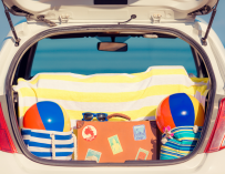Maletas, toallas y pelotas de playa en el maletero del coche.