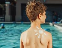 Niño en la piscina con crema solar