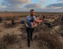 Un manifestante palestino carga a un joven herido en los enfrentamientos con el ejército de Israel en Gaza.