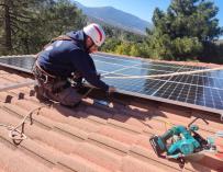 Un operario instala placas solares en una casa.