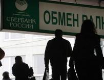 Un grupo de personas pasa por debajo de un anuncio de Sberbank, banco estatal ruso