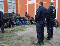 Policías vigilan a varios de los 51 inmigrantes tunecinos llegados de Italia que fueron arrestados por la Policía Nacional francesa.